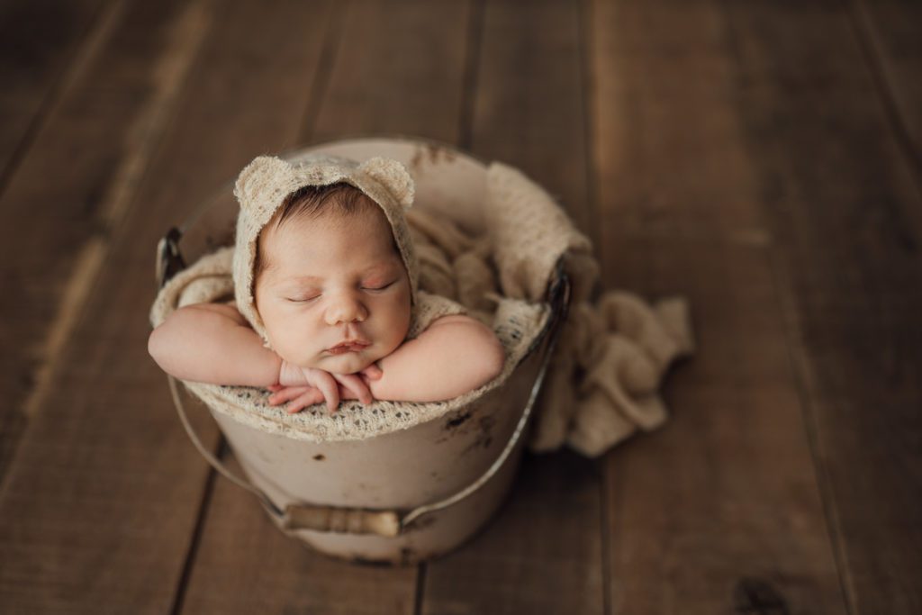 baby girl posed in bucket prop during studio newborn photo session in Tampa, FL