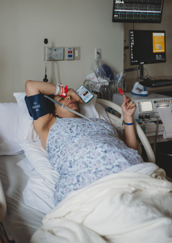 Mom holds popsicle and cell phone to breathe during contraction during birth in Annapolis, MD at AAMC